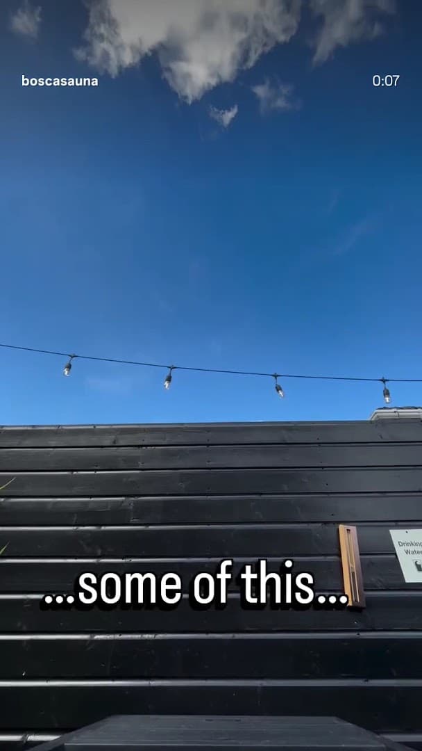A view of a black wooden building under a clear blue sky.