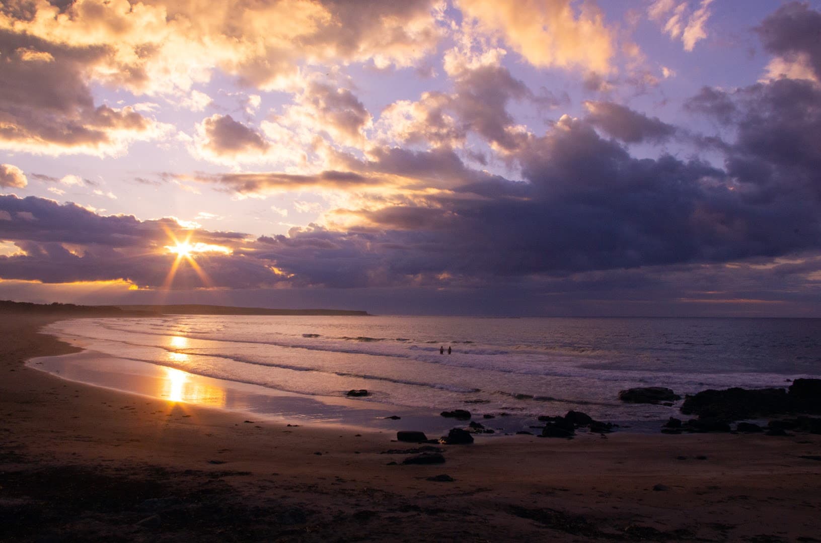 Sunset over the ocean at Dunmoran beach with clouds and gentle waves.