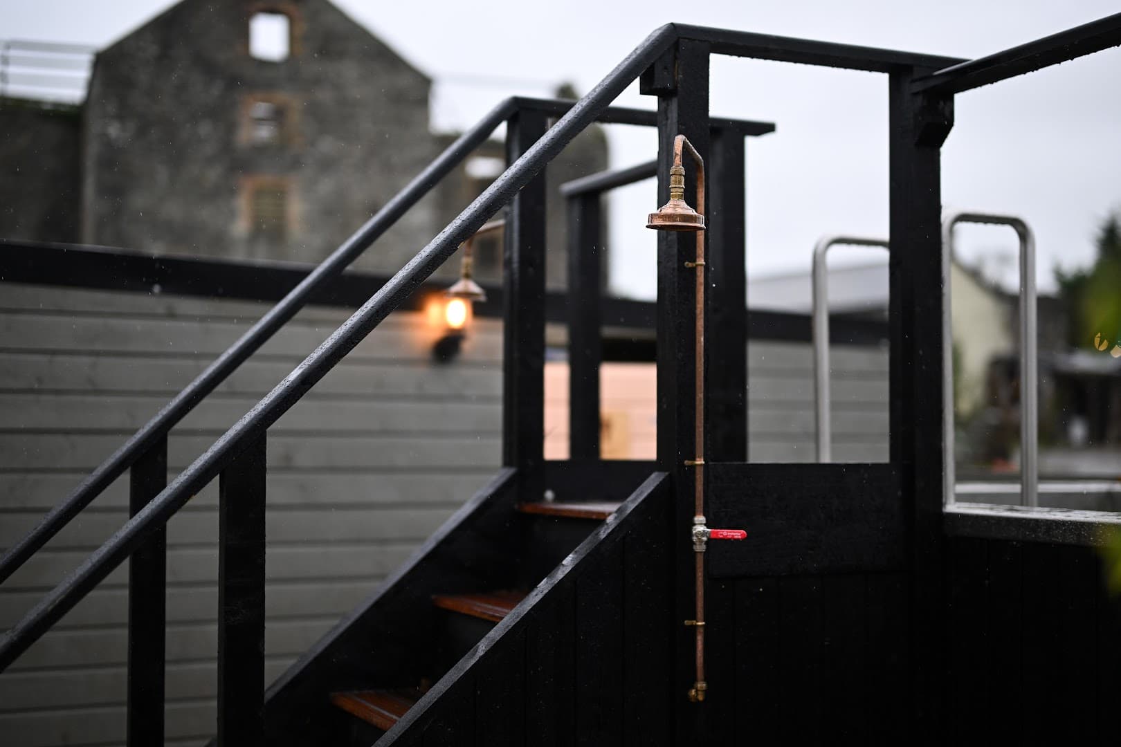 A black outdoor stairway with a copper shower pipe leads to a sauna in Ireland.